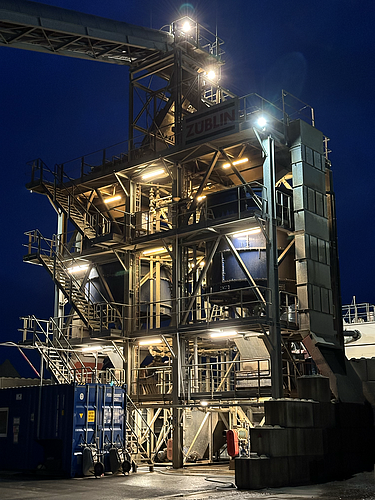 The soil-washing tower is brightly lit in the evening.