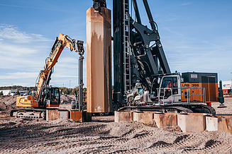 Honeycomb excavation for soil replacement: view of a drilling rig with leader-guided vibrator and excavator with long-arm grab